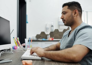 Dentista com computador vendo os principais meios de pagamento online para a sua clínica