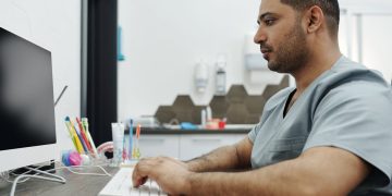 Dentista com computador vendo os principais meios de pagamento online para a sua clínica