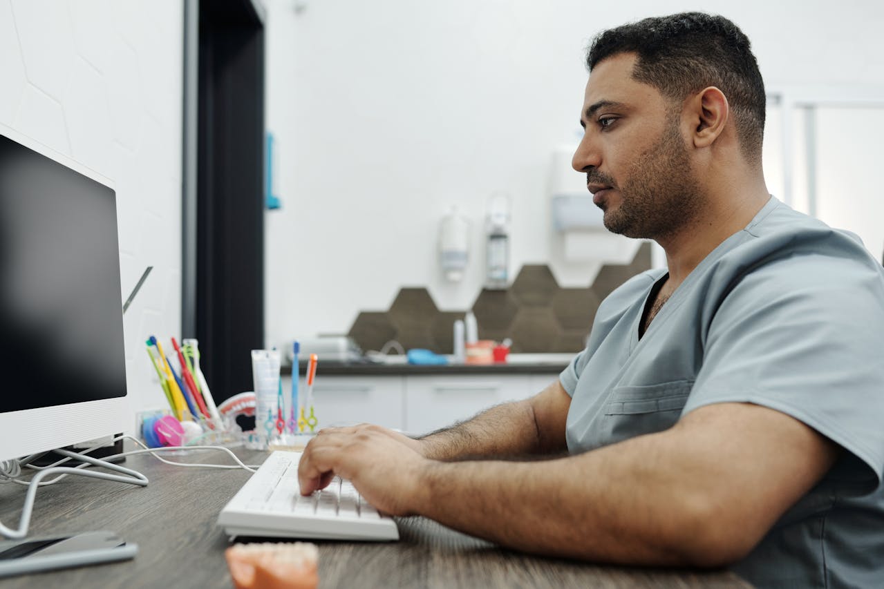 Dentista com computador vendo os principais meios de pagamento online para a sua clínica